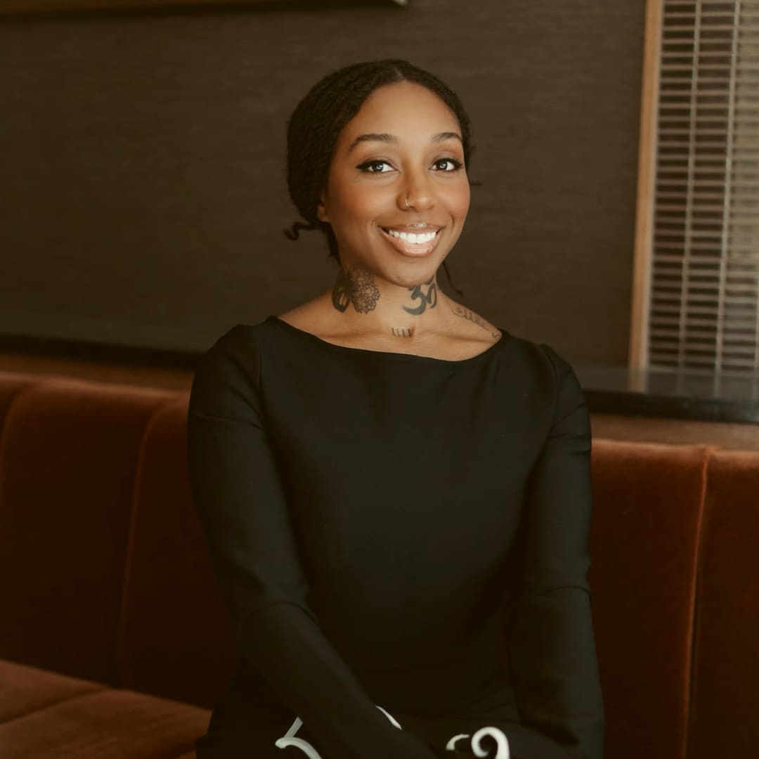 Asani Christie seated on a rust velvet banquette